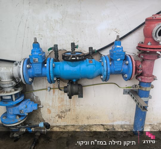 צינורות ושסתומים כחולים ואדומים על קיר לבן